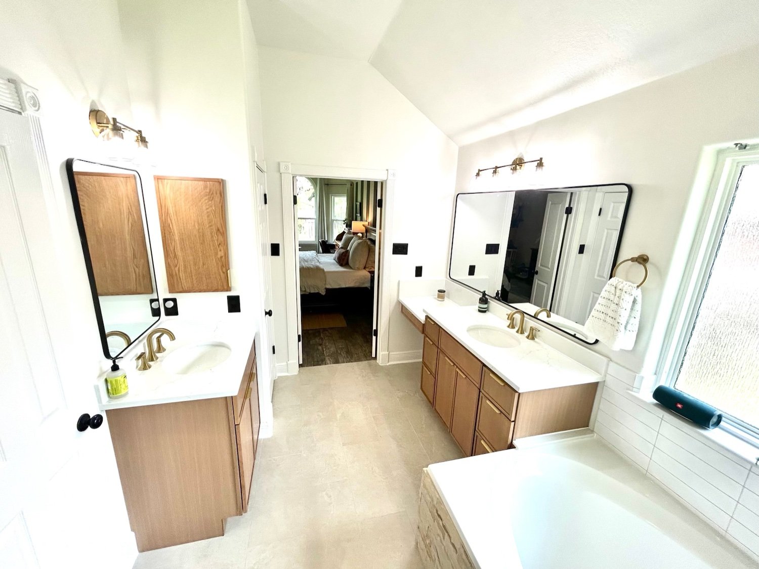Master bathroom remodel in Georgetown, TX with two white oak slab vanities, brass faucets, quartz countertops, and black rectangle mirrors